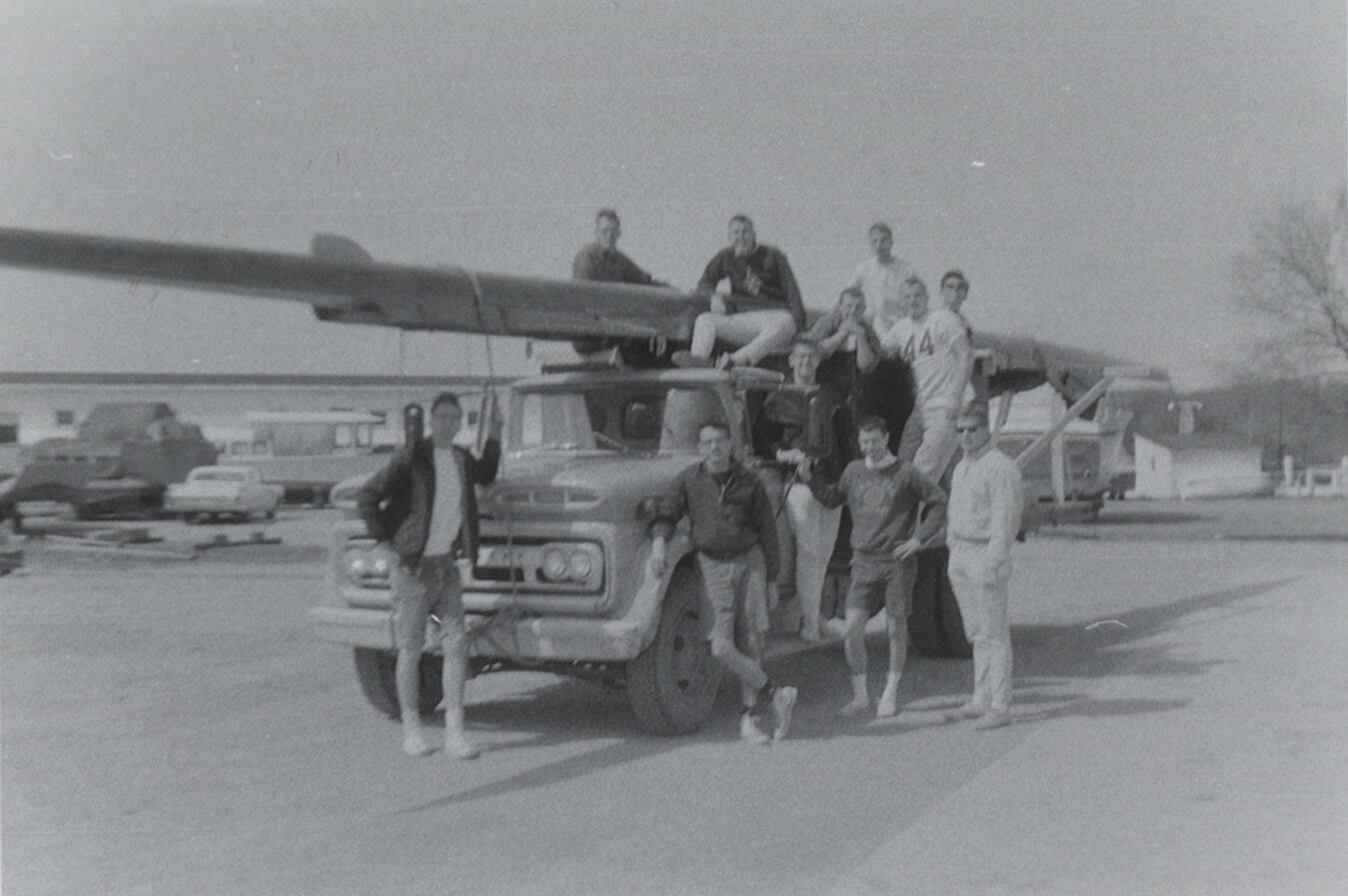 Rowing team standing next to a truck in 1964